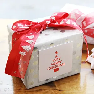 Christmas gift box packaging detail with red organza ribbon and holiday greeting card.