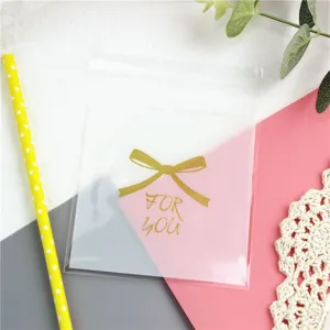 Detailaufnahme des transparenten Klebebeutels mit goldener Schleife und Aufdruck.