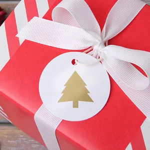Etiqueta de papel con árbol de navidad dorado, vista detallada de la decoración de regalo festiva.