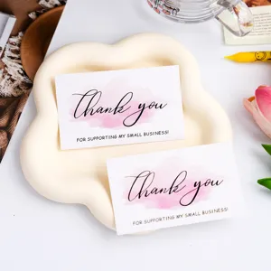 Detail view of thank you greeting cards with pink watercolor design on white cloud tray.