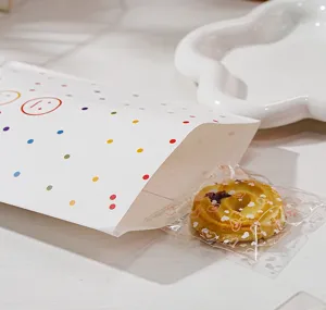 Vista dettagliata del grazioso sacchetto di carta a pois colorati con faccine giocose per regali.