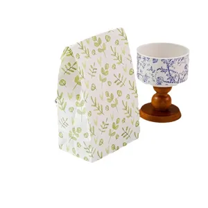 Bolsa de regalo ecológica con patrón de hojas verdes y taza de cerámica a juego con base.