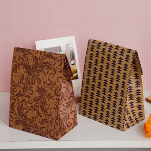 Detail view of retro kraft paper gift bags with leaf and geometric patterns on white desk.