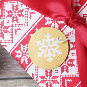 Etiqueta de Navidad redonda dorada con diseño de copo de nieve blanco para regalo festivo.