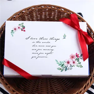 Gros plan détaillé d'une boîte cadeau de pâtisserie blanche à 6 compartiments avec ruban rouge.