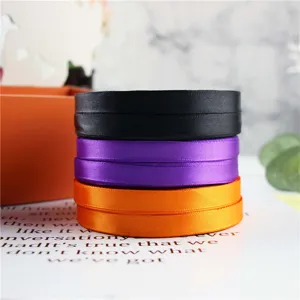 Details of 1cm satin ribbon rolls in black, purple, and orange for DIY gift wrapping.