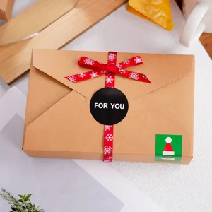 Scatola regalo in carta kraft a busta con nastro rosso e adesivo natalizio ideale.
