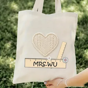 Vista de detalle de bolsa de lona para maestros con corazon tejido y regla, gran capacidad.