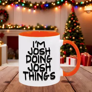 Detailaufnahme einer weißen und orangen Keramik Tasse mit englischem Spruch auf Tisch.