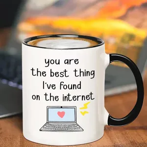 Nahaufnahme Detail einer Keramiktasse mit romantischem englischen Zitat und Laptop Grafiken.