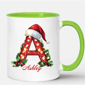 Taza de café de cerámica con letra navideña personalizada, hojas de acebo y asa verde festiva.