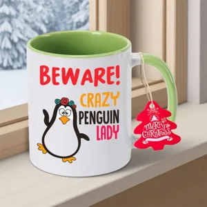 Detailansicht einer Keramiktasse mit Pinguin Motiv und Weihnachtsetikett am Fenster.