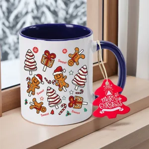 Detailed view of white ceramic coffee mug with blue handle, featuring cute Christmas gingerbread patterns.