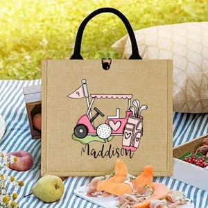 Gedetailleerde close-up van gepersonaliseerde golf jute tas met roze kar in picnicscène.