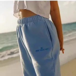 Detail shot of light blue women's jogger sweatpants with embroidery and elastic waist.