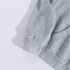 Close-up detail of casual grey hoodie sleeve, ribbed cuff and pocket stitching texture.