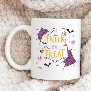 Detail view of a white ceramic coffee mug with cute Halloween Trick or Treat print.