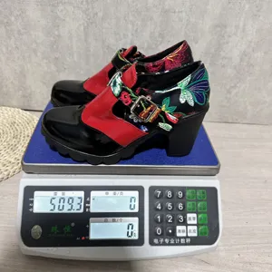 Vista detallada de zapatos de tacón grueso con elegante bordado floral y hebilla metálica.