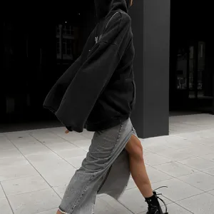 Vue détaillée d'un sweat à capuche noir oversize avec texte, assorti d'une jupe.