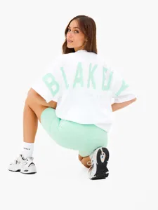 Dettaglio che mostra la stampa grafica posteriore, il taglio oversize e il colore verde menta.