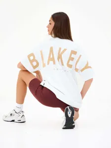 T-shirt bianco oversize a maniche corte con stampa dorata sul retro, stile streetwear.