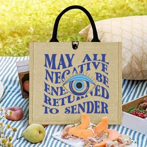 Detail view of the jute tote bag featuring evil eye print and mystical typography.