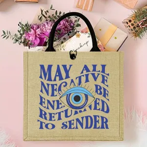 Mysterious evil eye pattern jute tote bag with black handles for daily use and shopping.