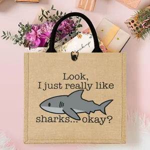Shark print jute tote bag detail shot, natural burlap material with sturdy black handles.