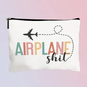 Detailaufnahme des weißen Canvas Kosmetiktags mit Flugmotiv und bunter Beschriftung.