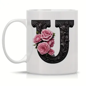 Close-up detail of white ceramic coffee mug featuring ornate black letter U and roses.