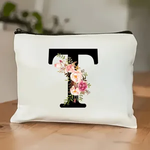 Nahaufnahme der weißen Kosmetiktasche aus Segeltuch mit schwarzem Buchstaben T und Blumen.