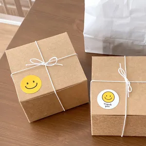 Kraft gift boxes set with white string ties and cute smiley face stickers, detailed view.