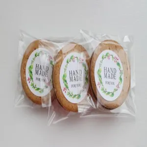 Detalle de galletas artesanales con pegatinas redondas y corona de hojas verdes para embalaje