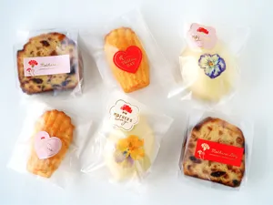 Vue de detail d'autocollants de la Fete des Meres avec oeillets et voeux sur des sachets cadeaux.