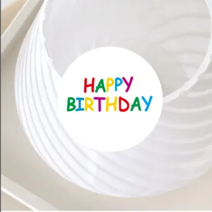 Detailed close-up view of colorful hand-written happy birthday sticker on clean white surface.