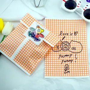 Detail view of cute orange checkered oil-proof paper bag with cartoon doodle for cookie packaging.