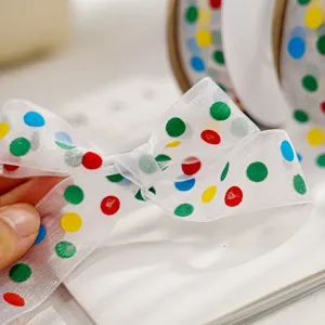 Close-up detail of colorful polka dot organza ribbon bow, sheer material, wrapping tape.