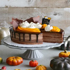 Heerlijke Halloween chocolade crepe taart met spookachtige room en feestelijke topper.