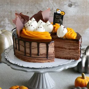 Heerlijke Halloween chocolade crêpetaart met spookcrème decoratie en enge feestelijke topper.