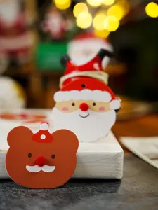 Christmas tag close-up detail: cute Santa and bear design with pom-poms for holiday gift decor.