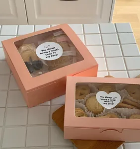 Boîte à biscuits rose avec fenêtre transparente et autocollant mignon pour cadeaux de fête.