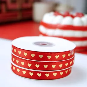 Detail du ruban rouge avec motif de cœurs en feuille d'or, ideal pour l'emballage cadeau.