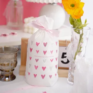 White plastic drawstring gift bag with pink heart patterns and ribbon for cookies and baking details
