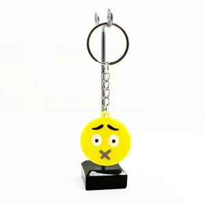 Detailopname van een schattige gele emoji PVC sleutelhanger op een metalen standaard.