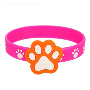 Nahaufnahme eines süßen pinken Silikonarmbands mit orange-weißer Pfotenabdruck-Charm.