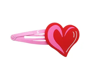 Nahaufnahme einer niedlichen rosa Metall-Haarspange mit rotem und rosa PVC-Herz-Anhänger.