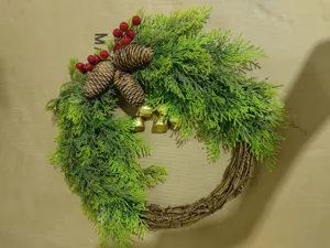 Gedetailleerd overzicht van handgemaakte kerstkrans met dennenappels, bessen en gouden bellen.