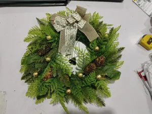 Handgemaakte kunstmatige kerstkrans met dennenappels gouden ballen en jute strik voor deurdecoratie.