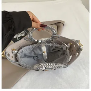Detailaufnahme einer stilvollen silbernen und grauen Handtasche mit geflochtenen Griffen.