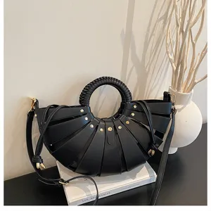 Detailaufnahme einer schicken schwarzen Beuteltasche mit geflochtenem Griff und Nieten.